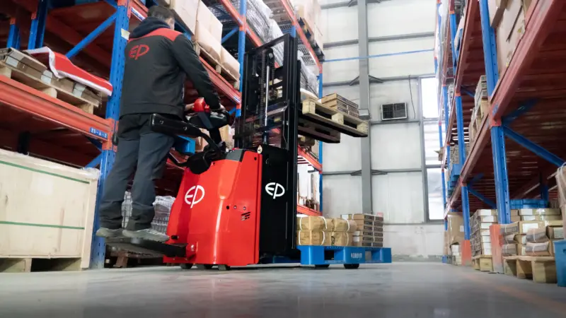 Xe nâng điện đứng lái RSi201 đang di chuyển hàng hóa trong kho cao